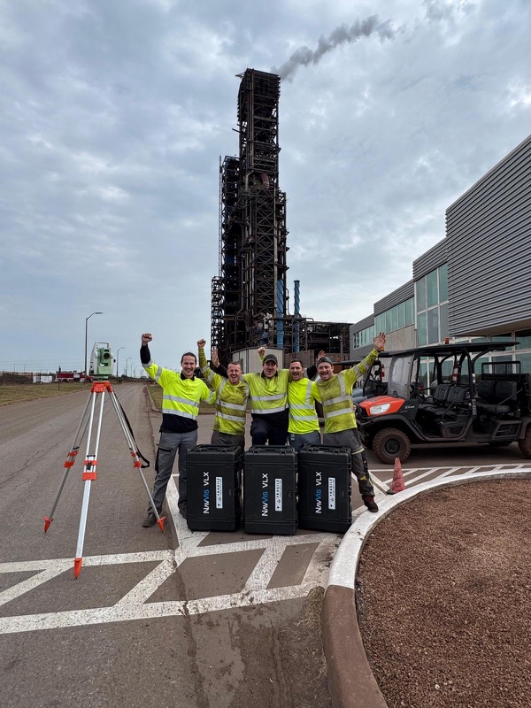 Survey team with a total station in front of a steel plant in Texas